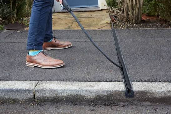Bündige Kabelrinne im Gehweg, in die ein Ladekabel eingelegt wird